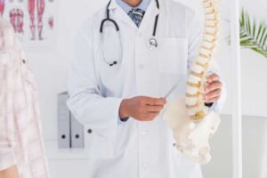 A chiropractor gently guides a patient's back while discussing treatment options in a comfortable clinic setting.