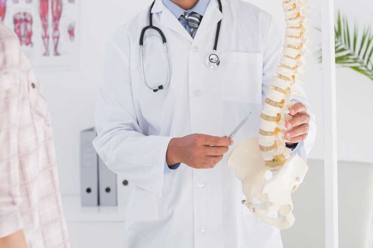 A chiropractor gently guides a patient's back while discussing treatment options in a comfortable clinic setting.