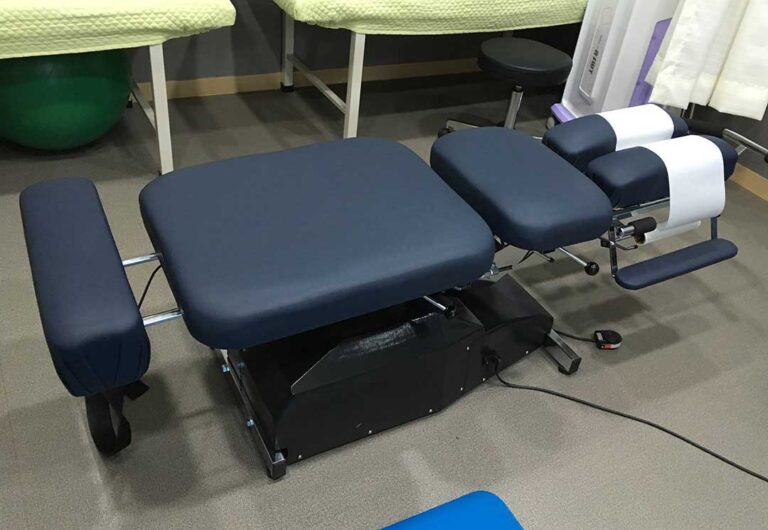 Athlete performing guided shoulder mobility exercises beside a treatment table.